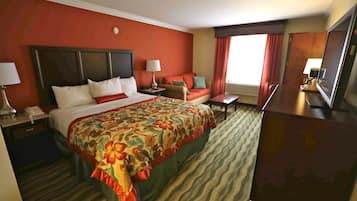 Habitación de hotel con una cama grande, un escritorio, una silla, un sofá y un televisor.