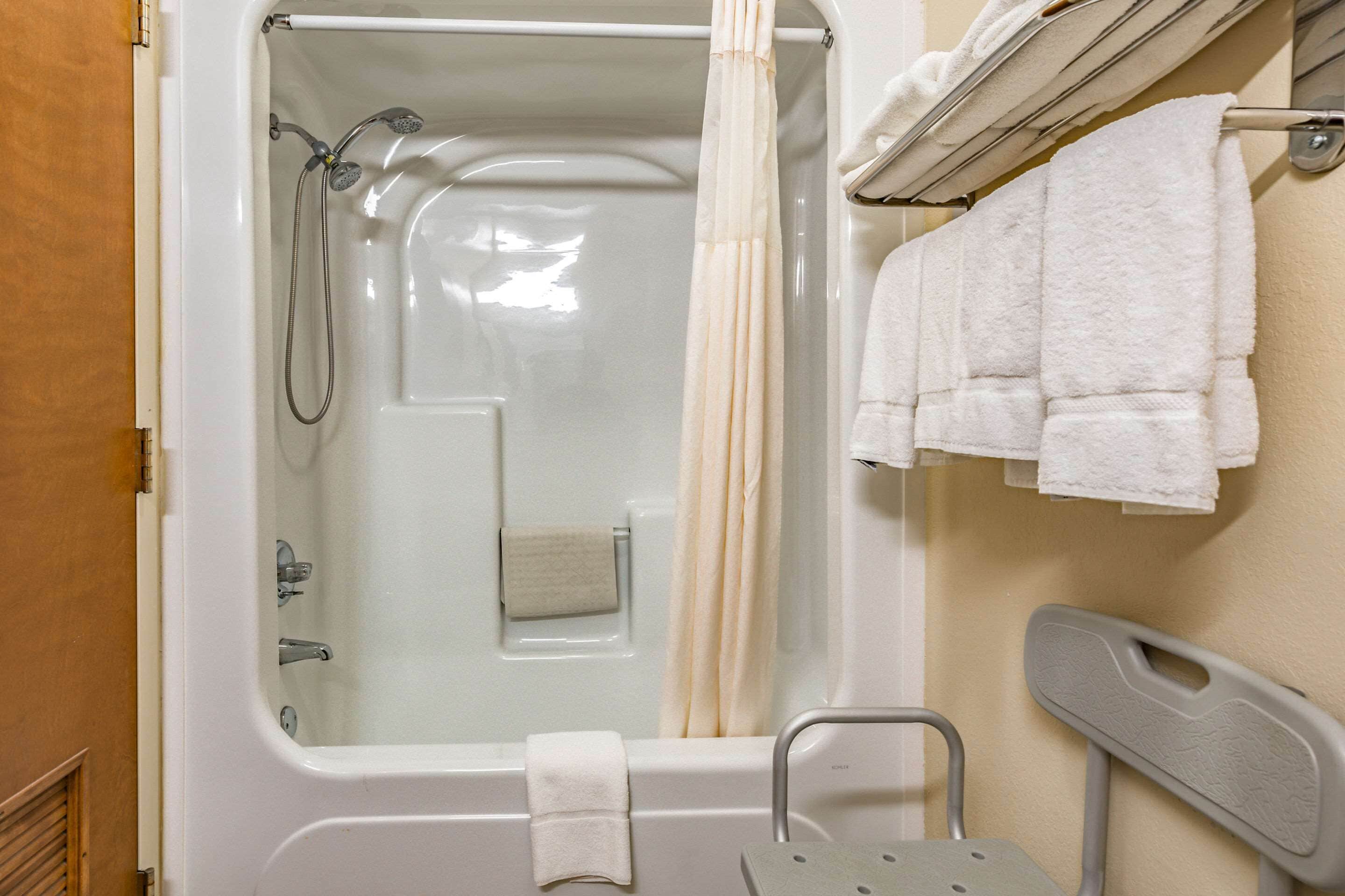 Une salle de bain équipée d’une baignoire, d’une douche, d’un porte-serviettes avec des serviettes et d’une barre d’appui.