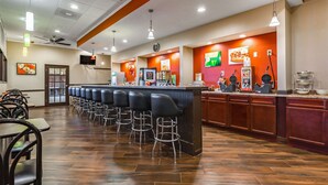 A restaurant with a bar area, multiple seating options, and a counter with food displays. - Quality Inn Schenectady - Albany (Schenectady)