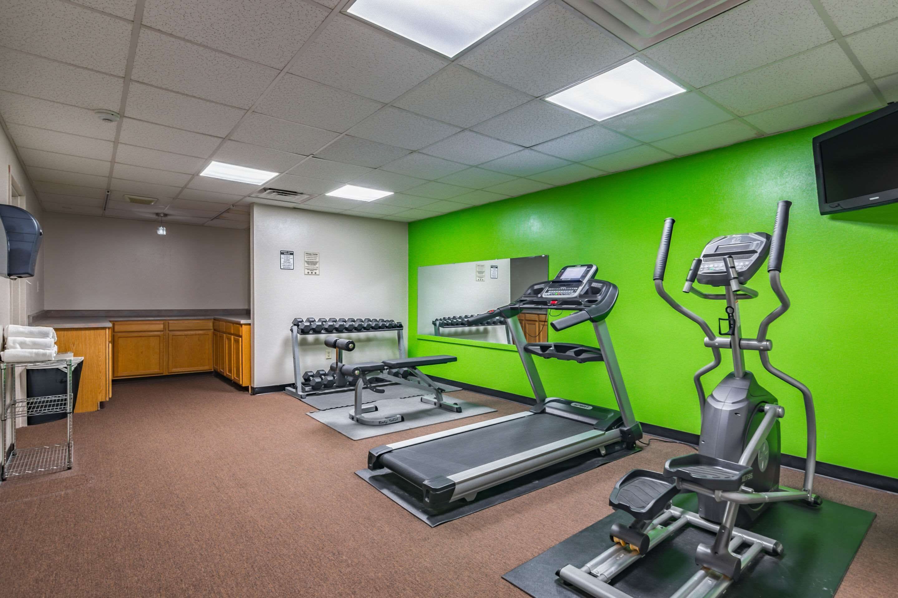 A fitness center with treadmills, elliptical machines, and a weight rack.