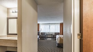 A hotel room with a bathroom, a bed, a desk, and a chair. - Quality Inn Schenectady - Albany (Schenectady)