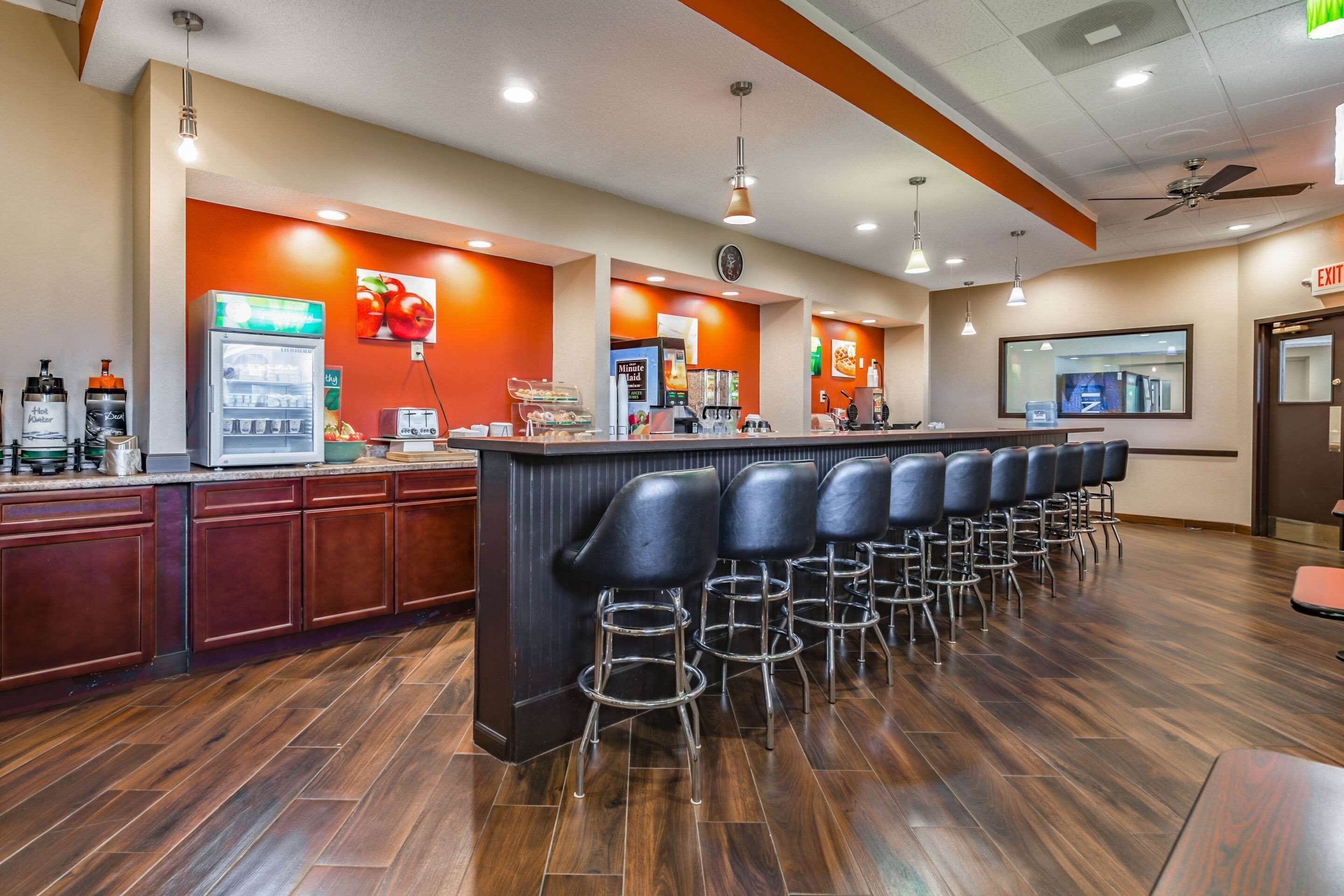 A bar area with a counter, stools, and a refrigerator.