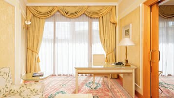 A room with a sofa, a table with a lamp, and a large window with curtains.