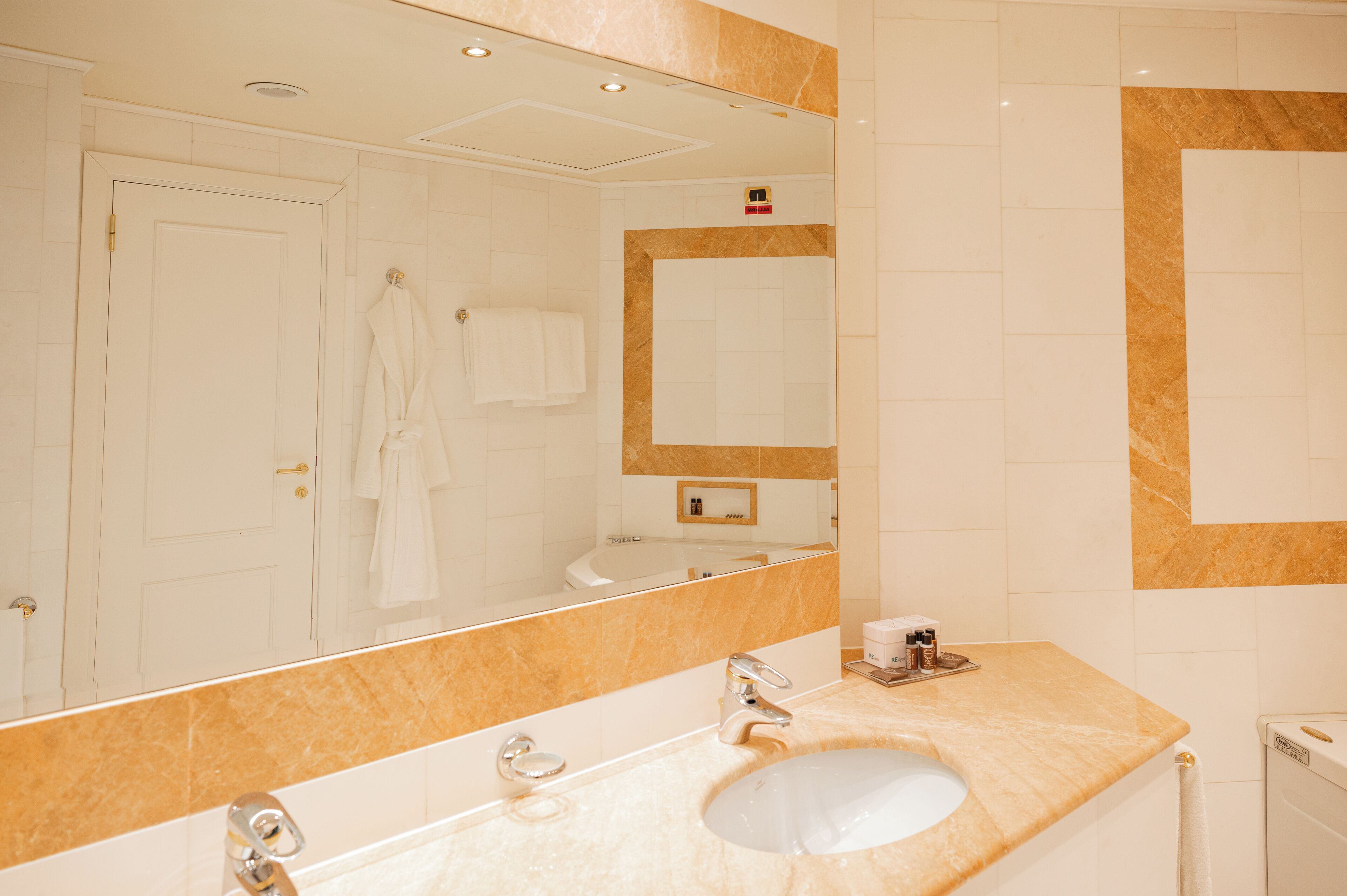 A bathroom with a large mirror, a sink, and a shower.