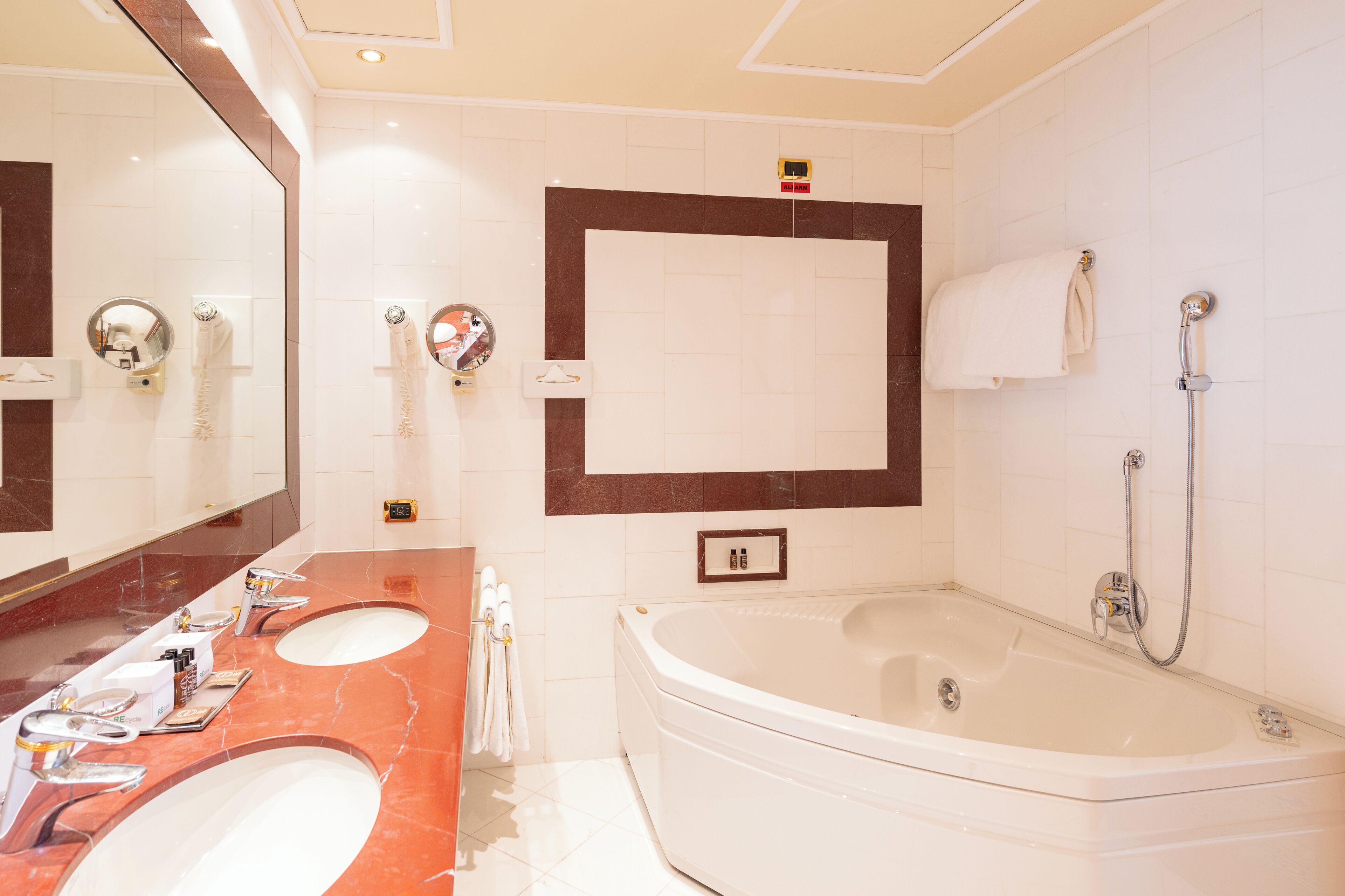 A modern bathroom with two sinks, a large mirror, a bathtub, and a towel rack.