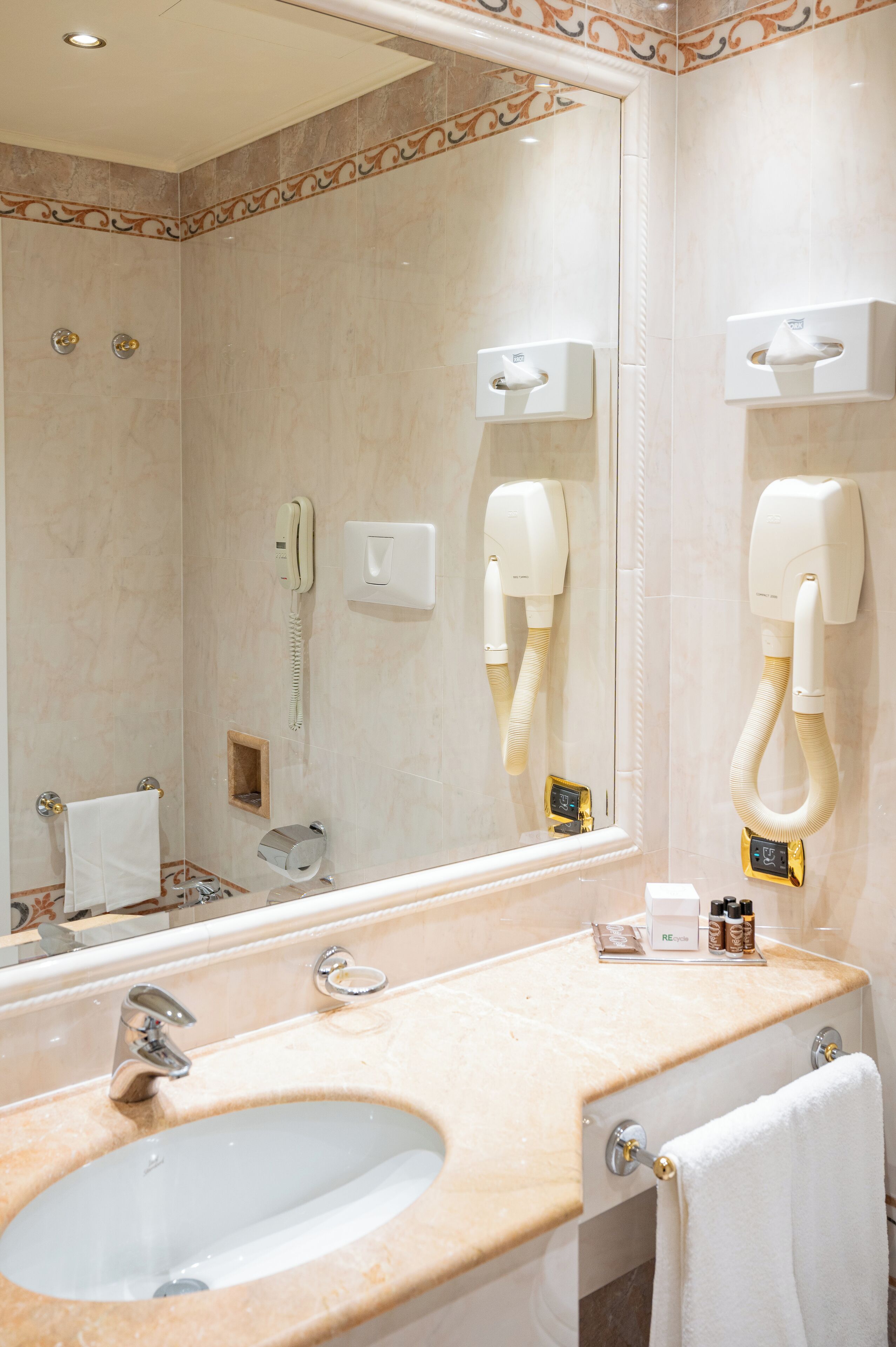 Ein Badezimmer mit Waschbecken, Spiegel, Handtuchhalter und Fön.