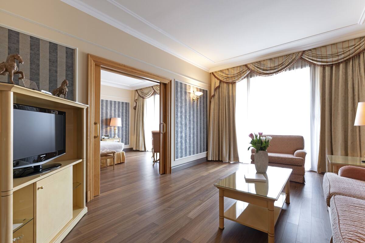 Une chambre d’hôtel équipée d’une télévision à écran plat, d’un canapé, d’une table basse et d’un coin repas.