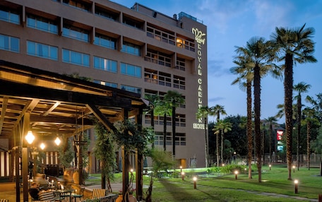 A hotel with a modern facade, outdoor seating area, and palm trees.