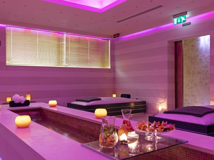 A spa area with a reception desk, seating, a small pool, and candles.