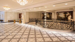 A grand lobby with a marble floor, ornate railings, and a large painting on the wall. - Royal Hotel Carlton (Bologna)