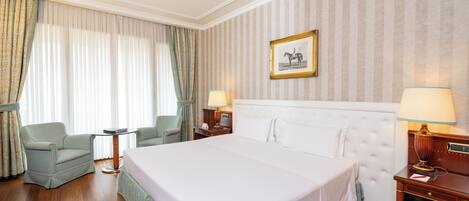 Une chambre d’hôtel avec un grand lit, deux tables de chevet avec des lampes, une chaise et des rideaux.