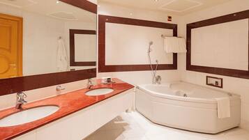Un baño con dos lavamanos, una bañera y un espejo grande.