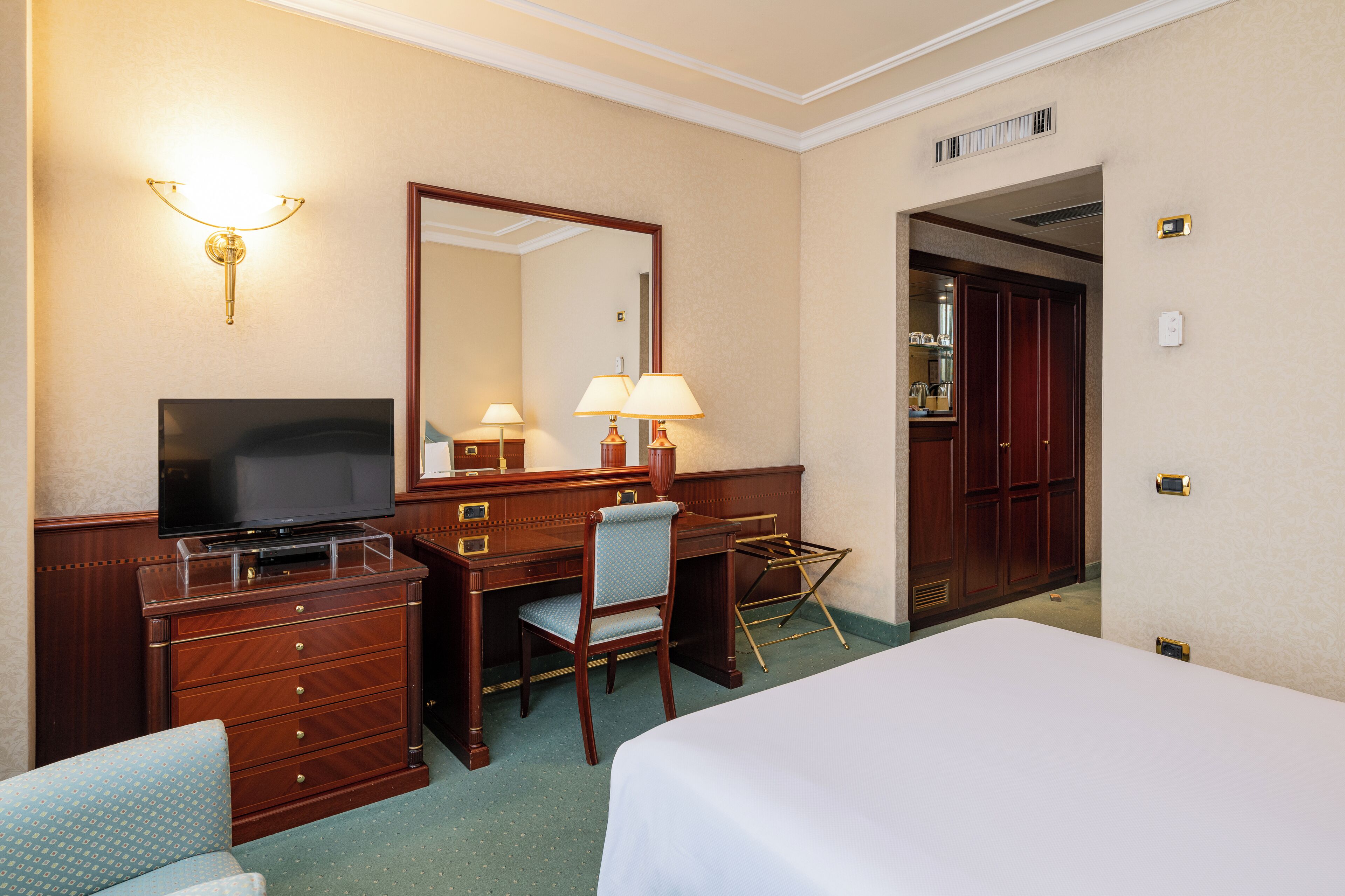 Une chambre d’hôtel comprenant un lit, un bureau avec une chaise, une télévision et un miroir.