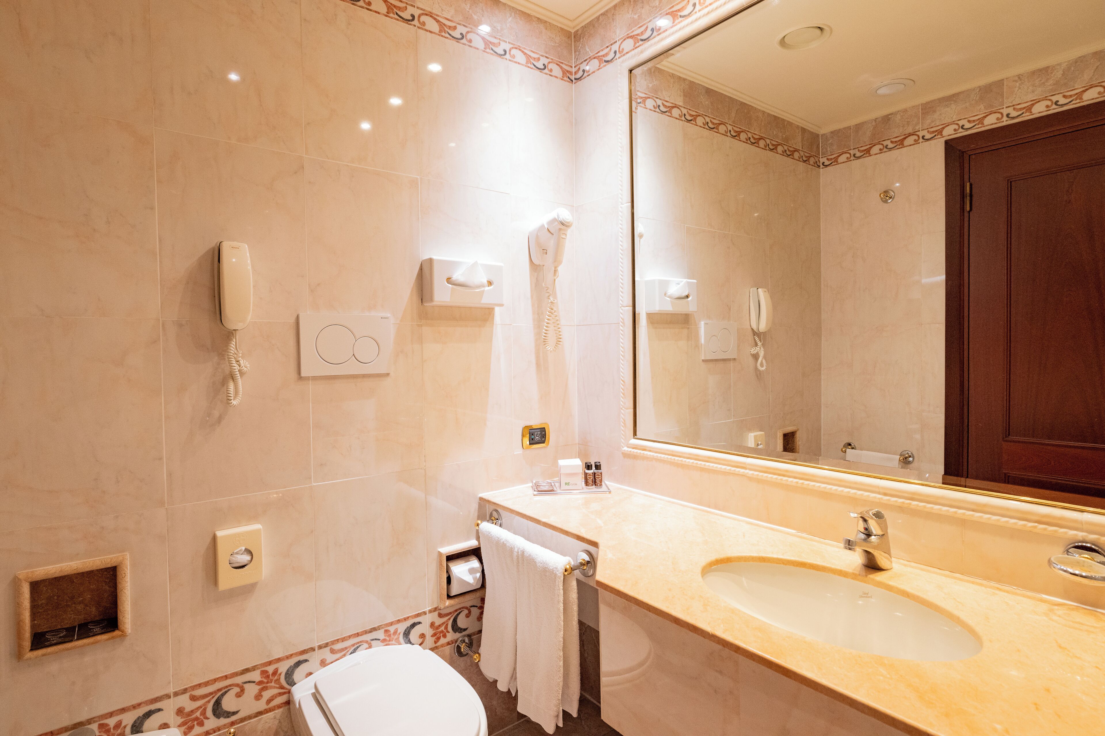 Ein Badezimmer mit Waschbecken, Spiegel, Handtuchhalter und Toilette.