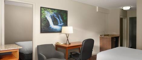 Habitación de hotel con dos camas, un escritorio, una silla, un teléfono y un cuadro de una cascada.