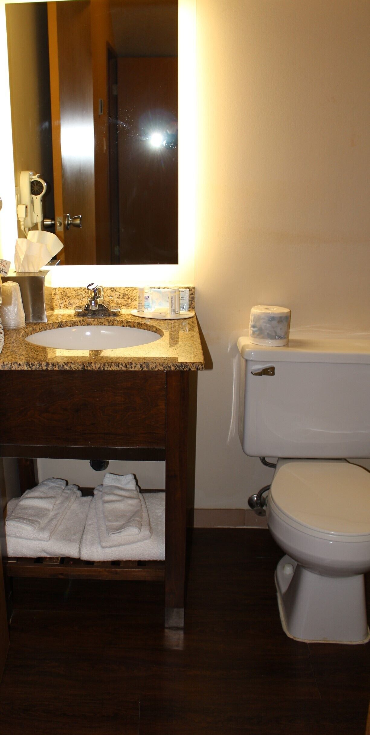 Un baño con lavabo, espejo, inodoro y toallero.