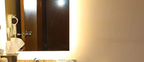 Un baño con lavabo, espejo, inodoro y toallero.