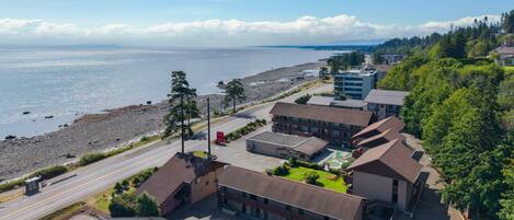 A coastal hotel with multiple buildings, a parking lot, and a view of the beach and ocean.