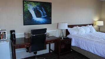 Ein Hotelzimmer mit Bett, Schreibtisch, Stuhl und einem großen Wandbild mit einem Wasserfall.