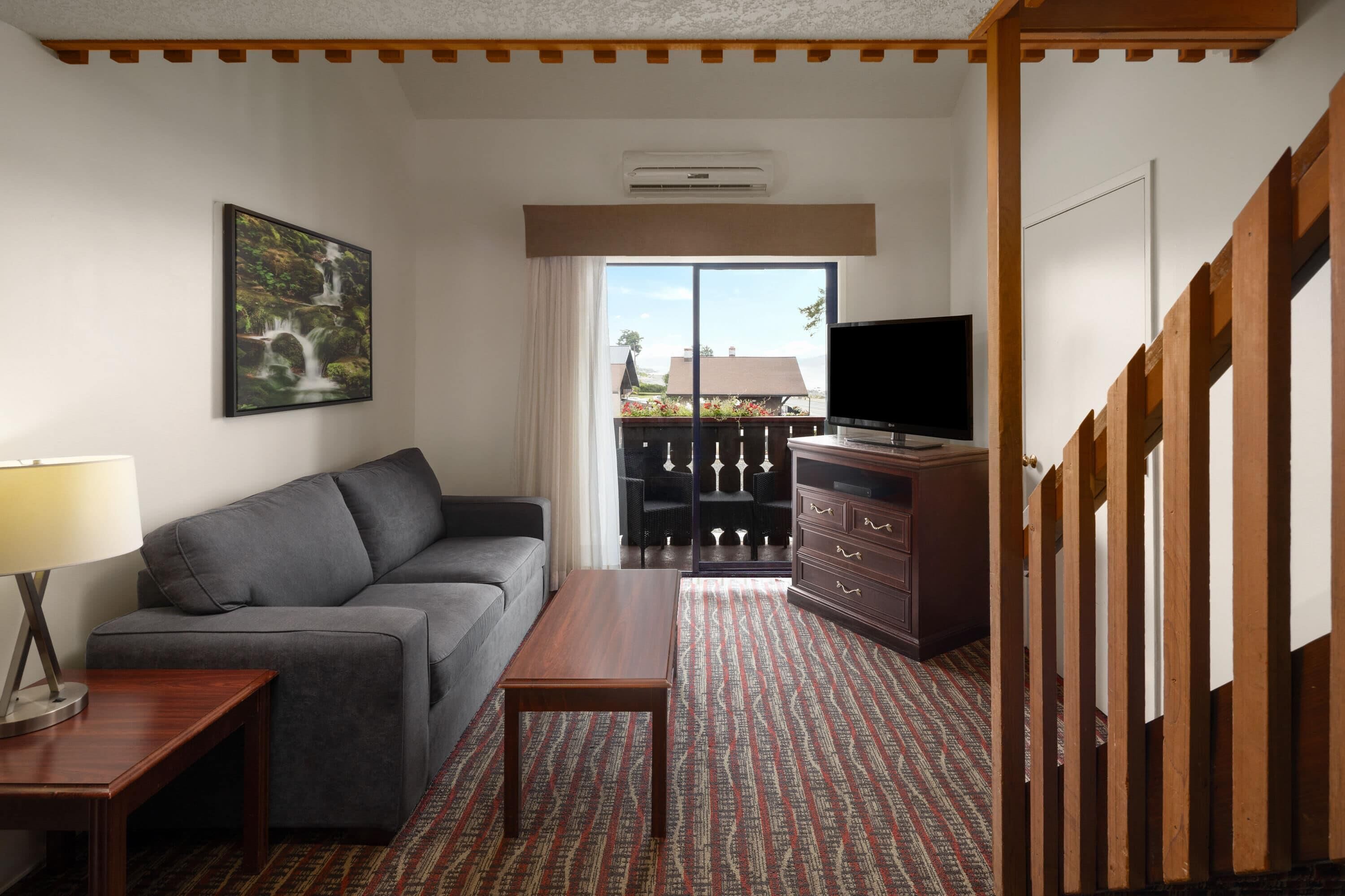 A living room with a sofa, a coffee table, a TV, and a painting on the wall.