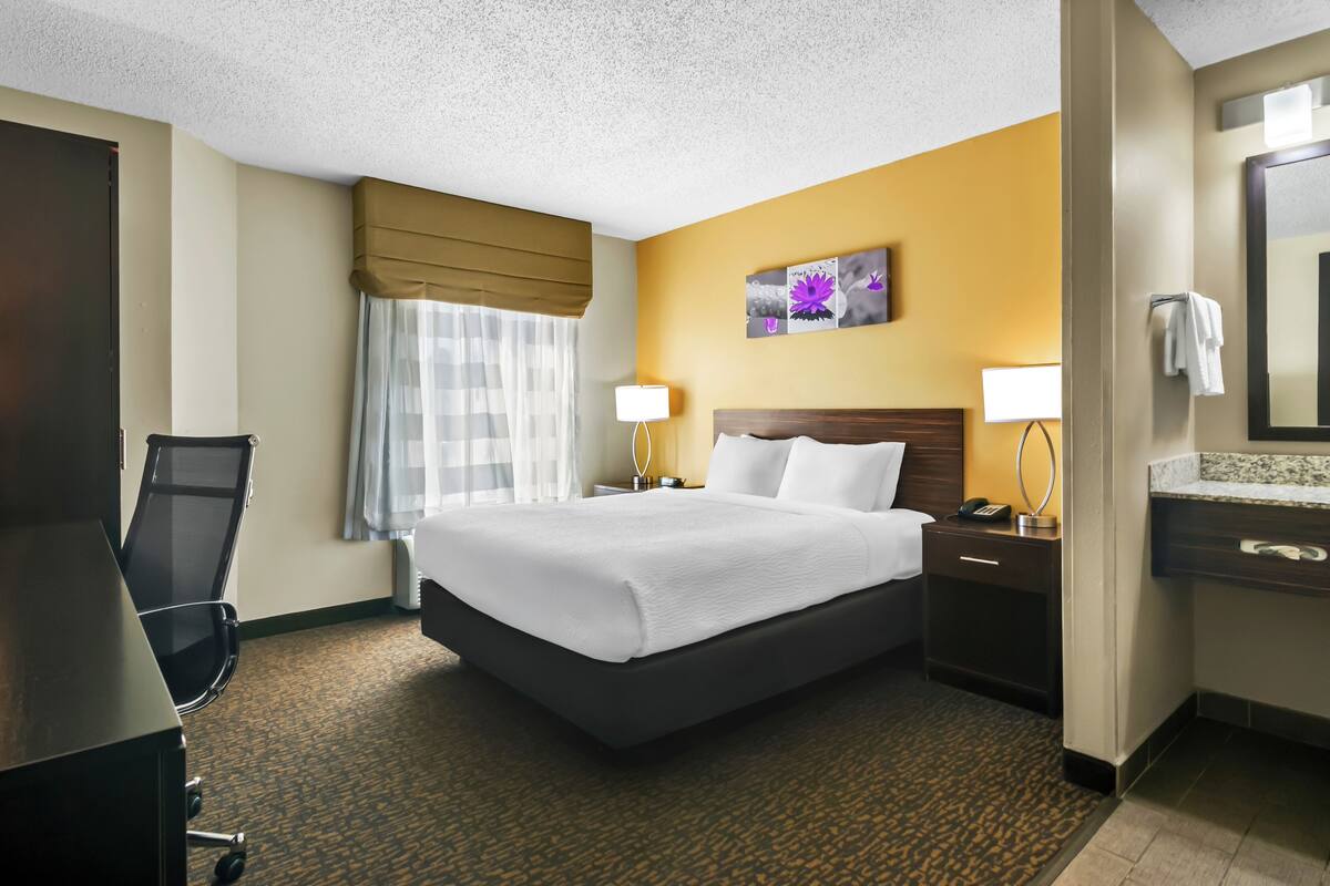 A hotel room with a large bed, bedside tables, a desk, and a chair.