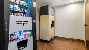 A vending machine with snacks and drinks, a microwave, and a door in a hallway. - Sleep Inn Fayetteville North (Fayetteville)
