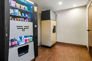 A vending machine with snacks and drinks, a refrigerator, and a wooden floor in a hotel room. - Sleep Inn Fayetteville North (Fayetteville)