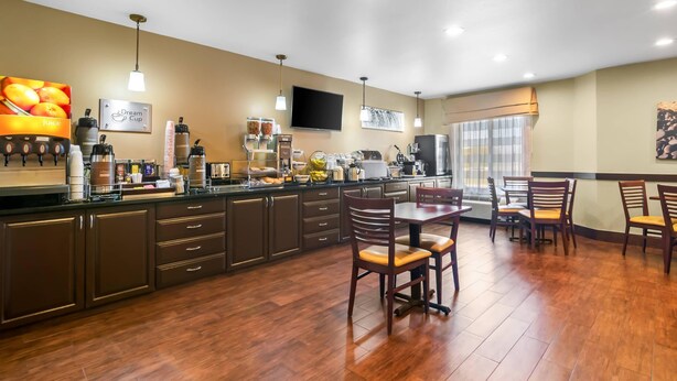 Una cocina moderna con alacenas de madera oscura, una isla central y un comedor con sillas de madera.