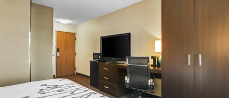 A hotel room with a bed, a desk with a computer, a television, and a wardrobe.