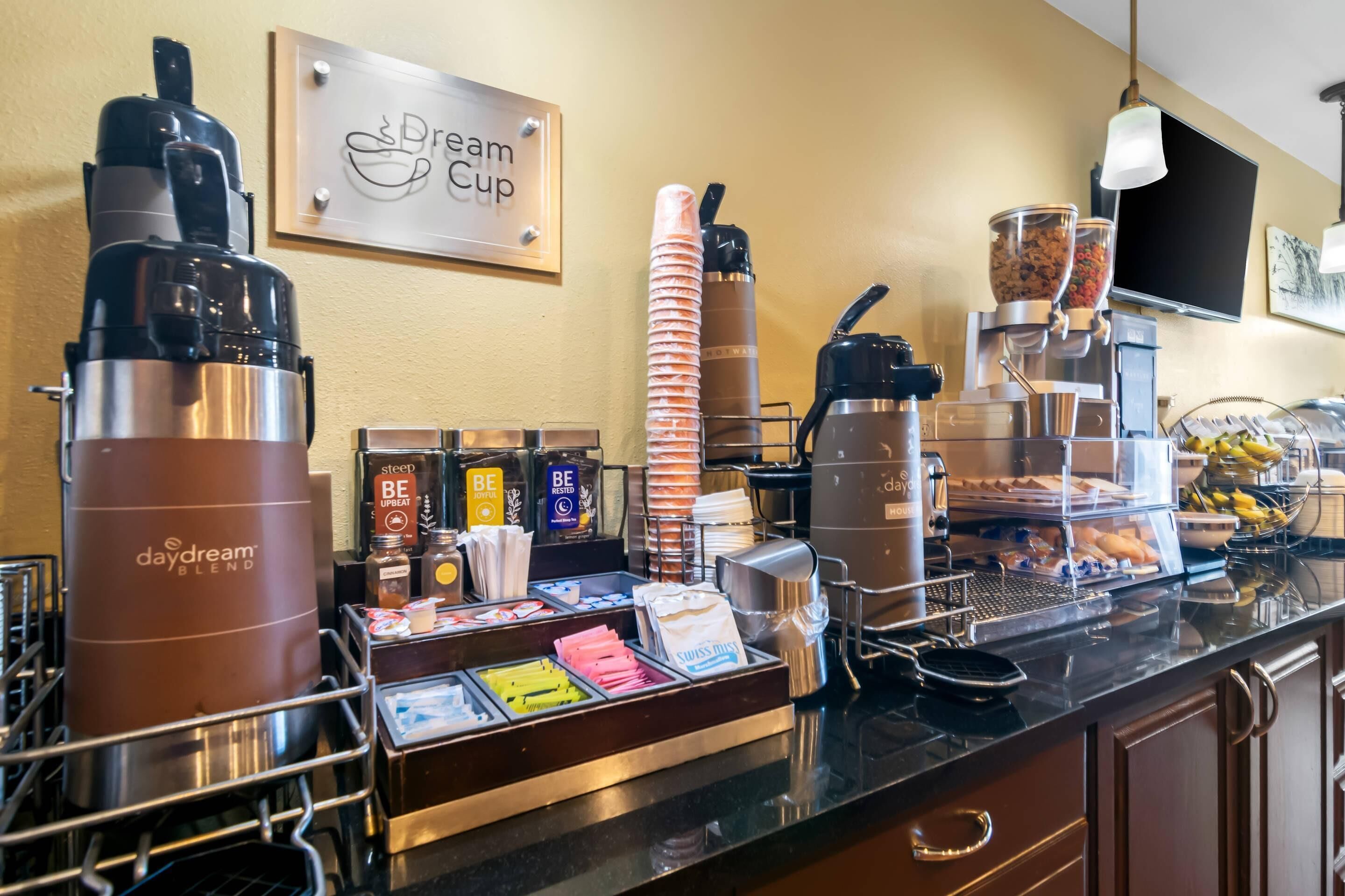 A coffee station with branded dispensers, a coffee machine, and a variety of coffee pods and creamer options.