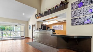 Un área de recepción con diseño moderno, que cuenta con una mesa de recepción, un ventanal grande y un mostrador de atención al cliente.