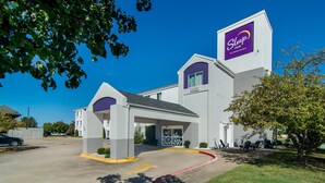 Edificio de Sleep Inn, una marca de Choice Hotels, con entrada cubierta, estacionamiento y zona verde con mesas al aire libre.