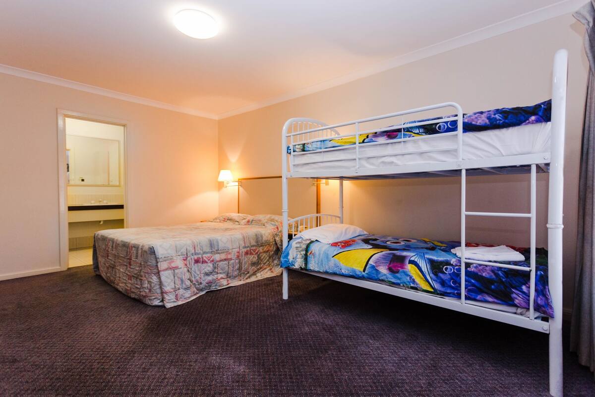 A room with two bunk beds, a door, and a wall-mounted lamp.