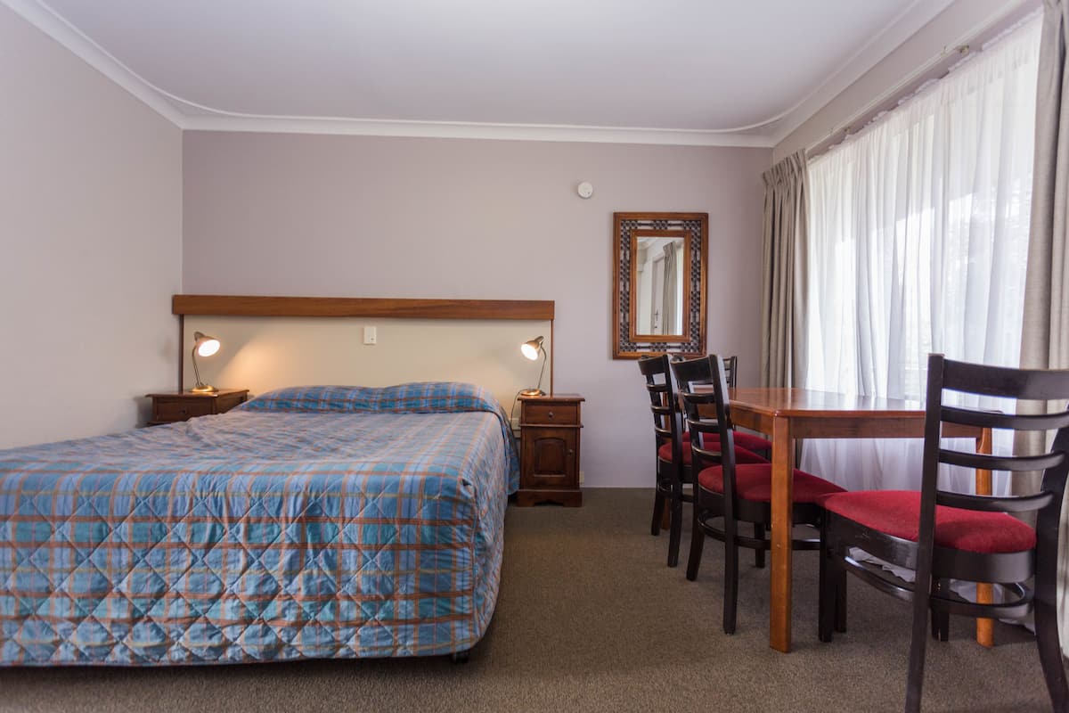 A bedroom with a bed, bedside tables, a desk, and chairs.