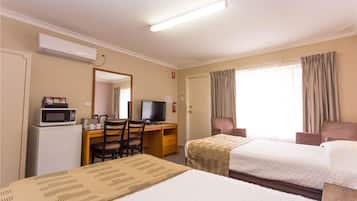 A hotel room with two beds, a desk with a computer, a microwave, and a TV.
