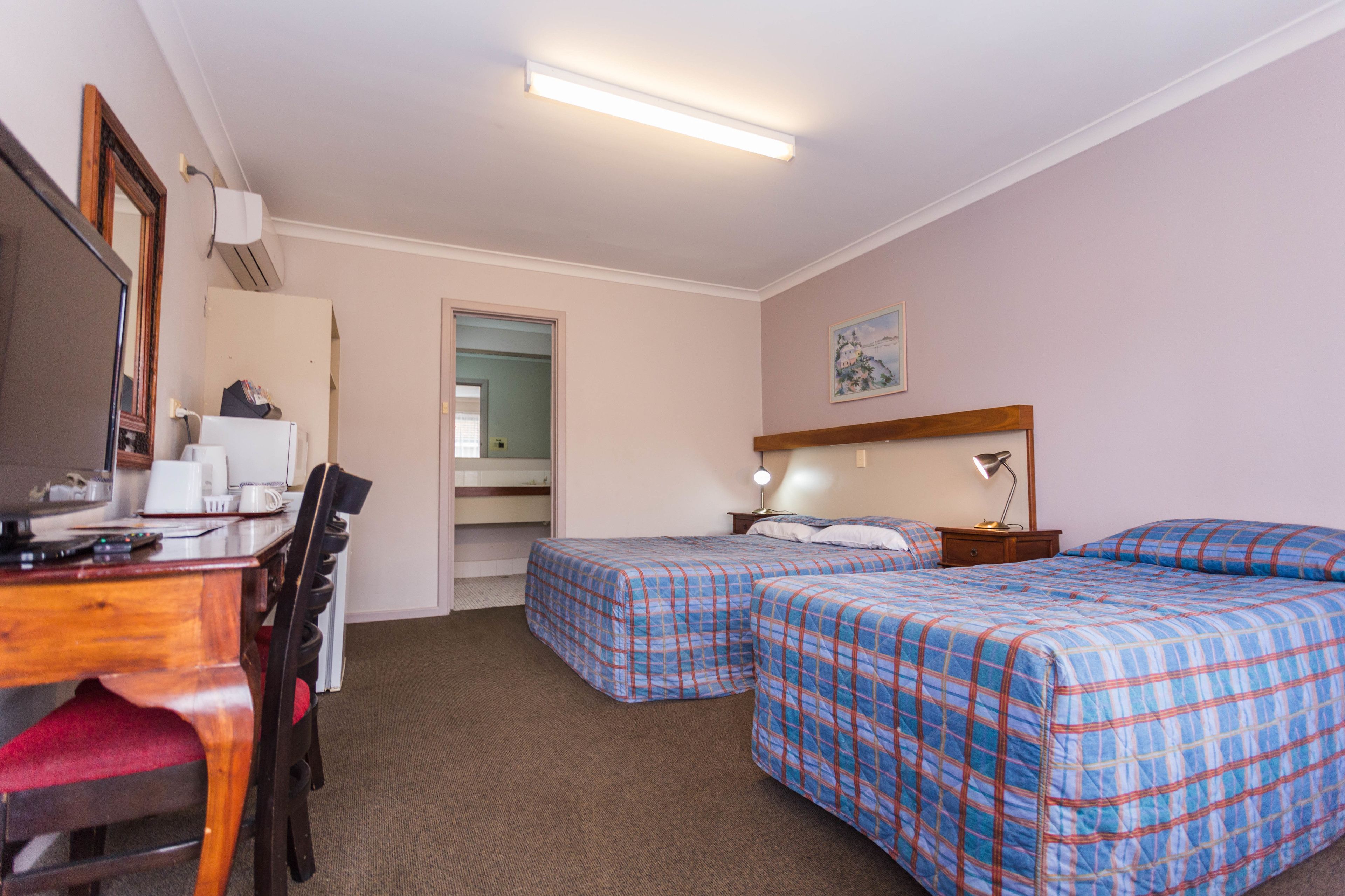 A hotel room with two beds, a desk with a chair, a TV, and a mirror.