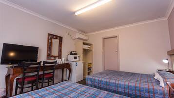 Une chambre d’hôtel avec deux lits, un bureau avec une télévision, un four à micro-ondes et une porte.