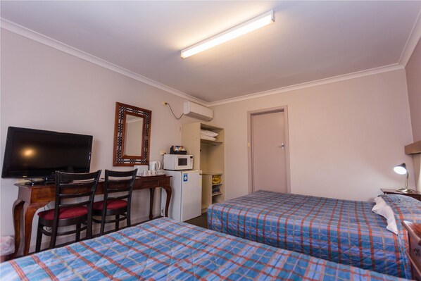A hotel room with two beds, a desk with a TV, a microwave, and a door. - Sleepwell Motel (Centennial Park)