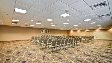 A conference room with rows of chairs, a patterned carpet, and a ceiling with recessed lighting.