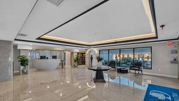 A modern lobby with a reception desk, seating area, and large windows offering a view of the outdoors.