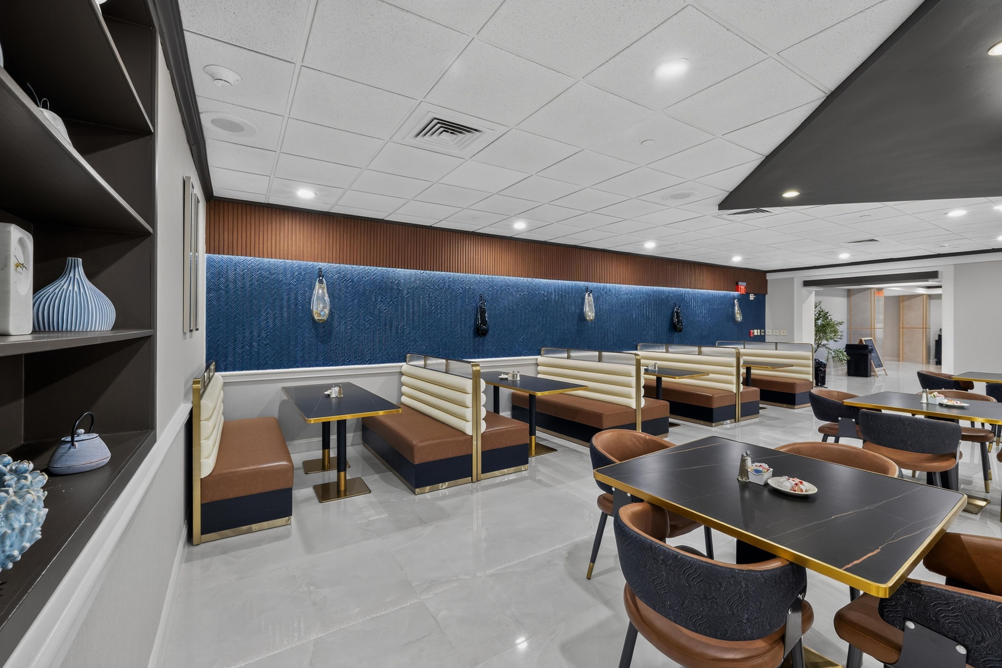 A modern restaurant with booths and tables, a blue textured wall, and a clean, tiled floor.