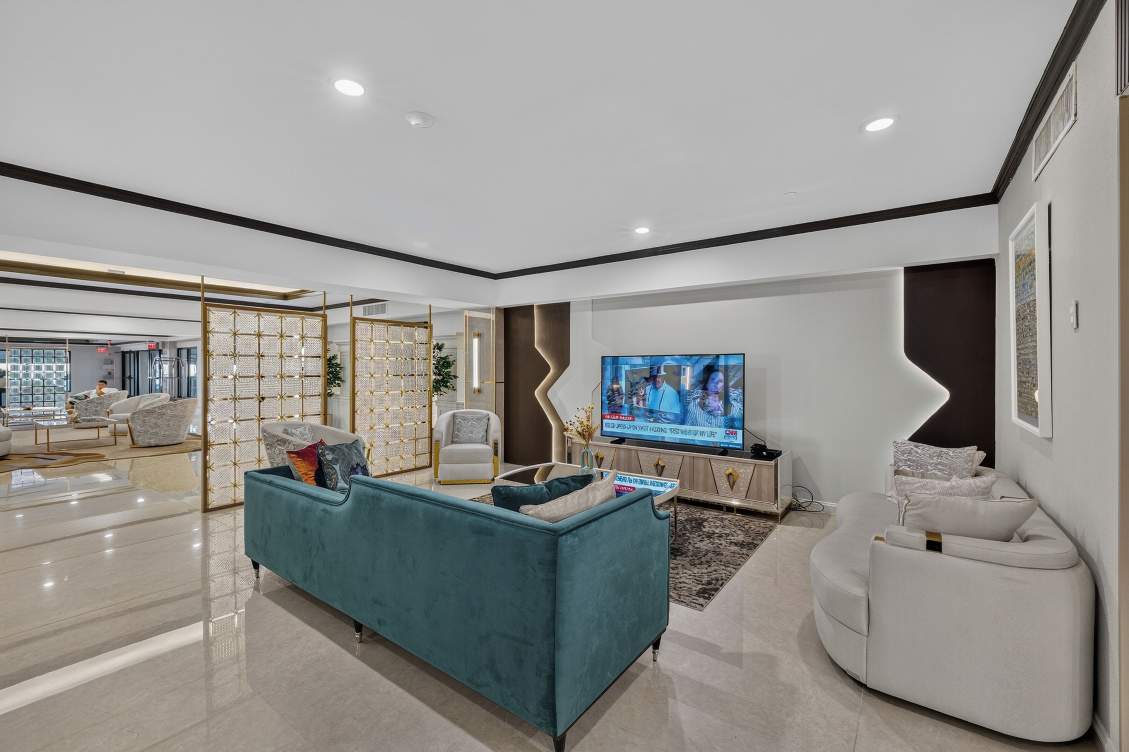 A modern living room with a teal sofa, white armchairs, a flat-screen TV, and a decorative partition.