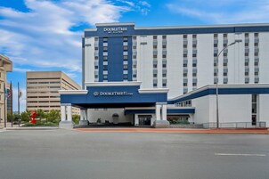 Un hotel DoubleTree by Hilton con fachada moderna, una entrada destacada y cielo despejado.