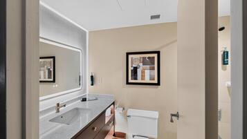 A modern bathroom with a double sink vanity, a toilet, and a framed abstract artwork on the wall.