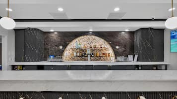 A bar area with a marble countertop, a selection of liquor bottles, and a herringbone patterned wall.