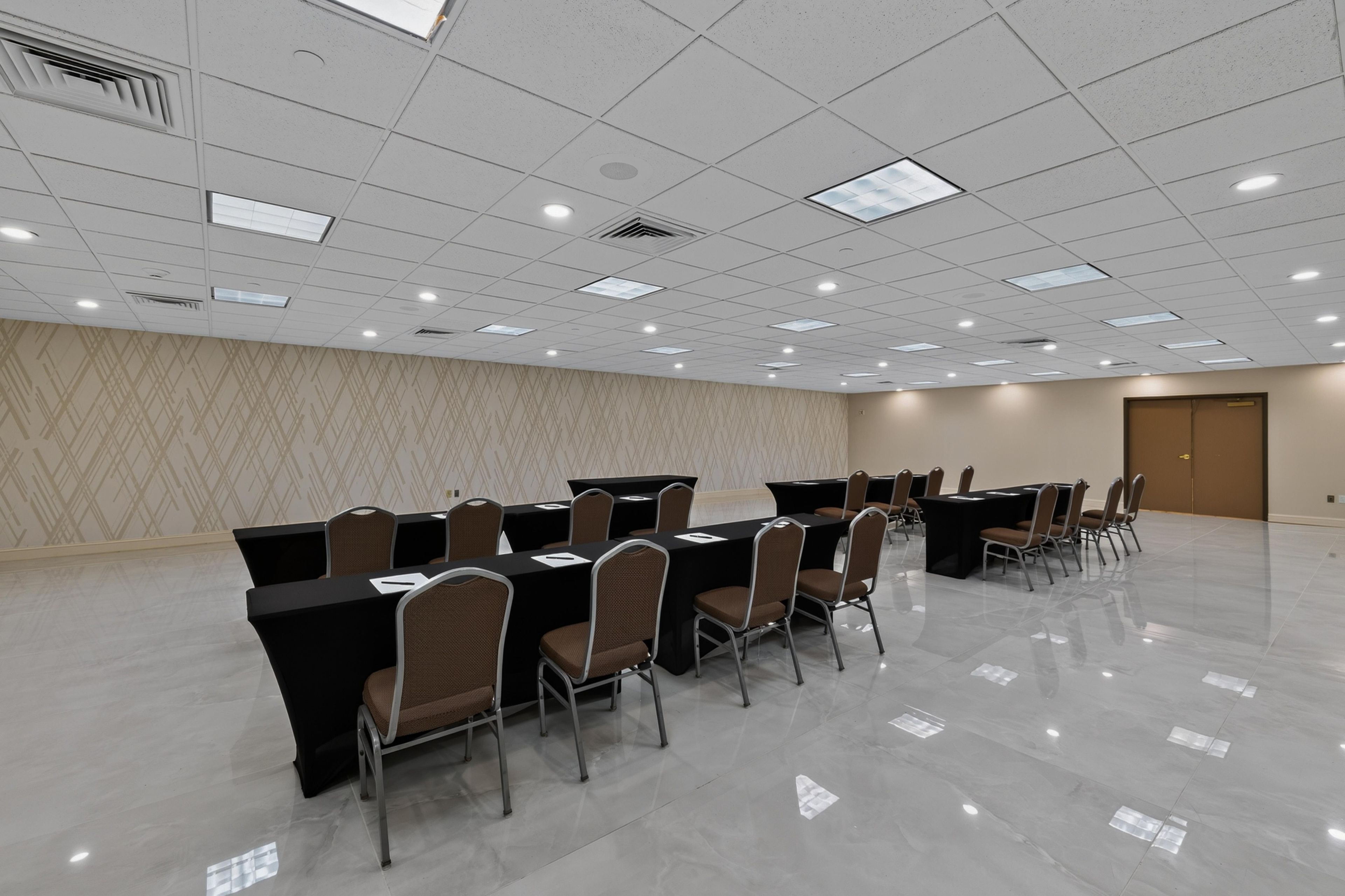 Un salón de conferencias con varias mesas y sillas, un papel tapiz decorativo y una puerta.