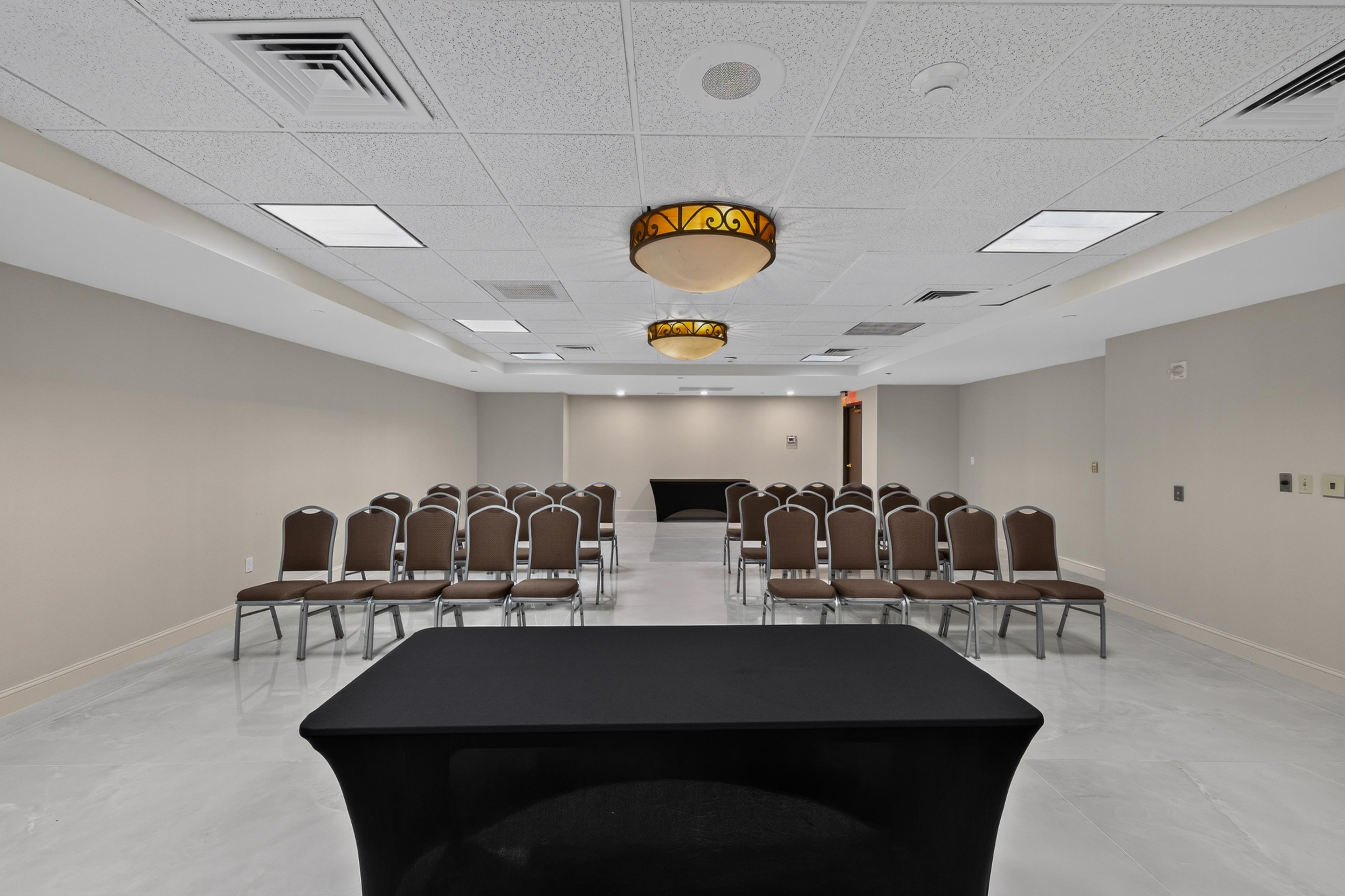 A conference room with a long table, rows of chairs, and a stage at the front.