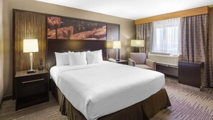 A hotel room with a large bed, two bedside tables with lamps, a chair, a large painting on the wall, and a window with curtains. - DoubleTree by Hilton Downtown Wilmington - Legal District (Wilmington)