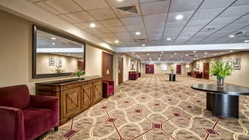 Een hotel lobby met een kamerbreed tapijt, een receptiebalie en een zithoek met een rode bank.
