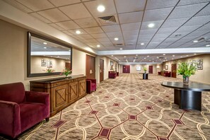 A hotel lobby with a patterned carpet, a reception desk, and a seating area with a red sofa.